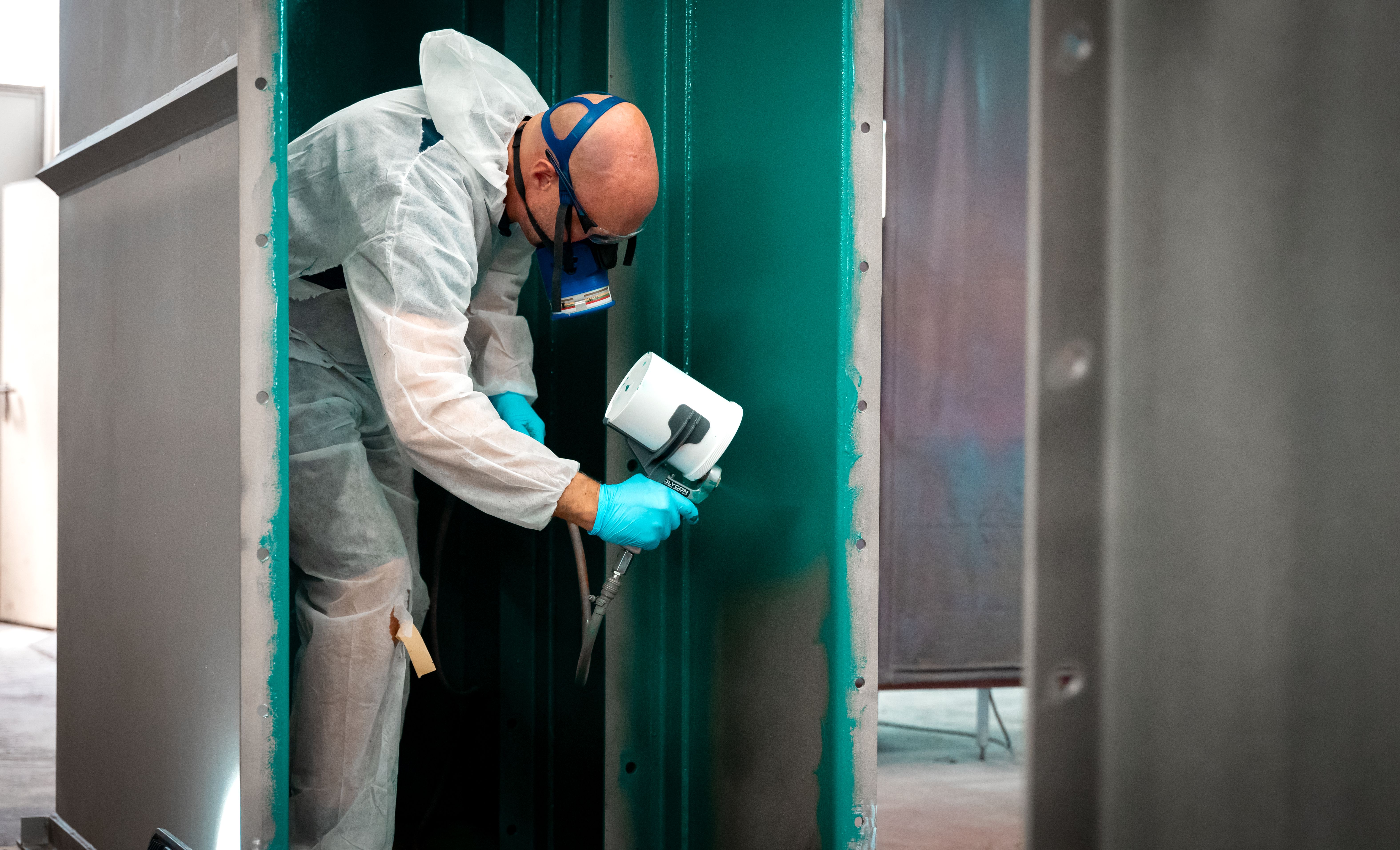 A man wearing a mask sprays on a green control layer